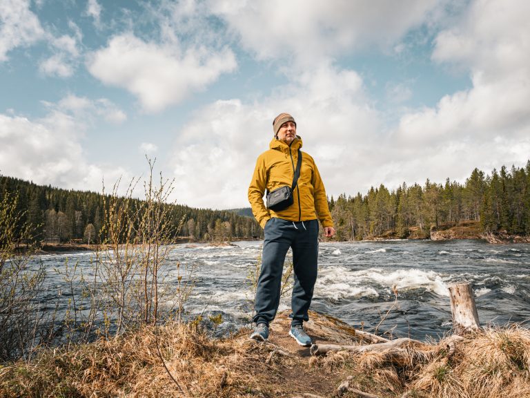 Outdoorporträt eines Mannes an einem Flussufer – Naturaufnahme mit Wald, Wasser und Weitblick