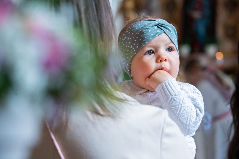 Nahaufnahme eines Babys bei familiärem Anlass – emotionale Momentaufnahme während einer Taufe in Tirol
