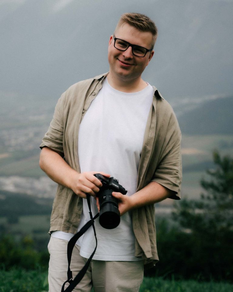 Julian Haberl, Gründer von JH‑Creative in Thaur, mit Kamera vor Alpenpanorama – professioneller Foto‑ und Videograf aus Tirol