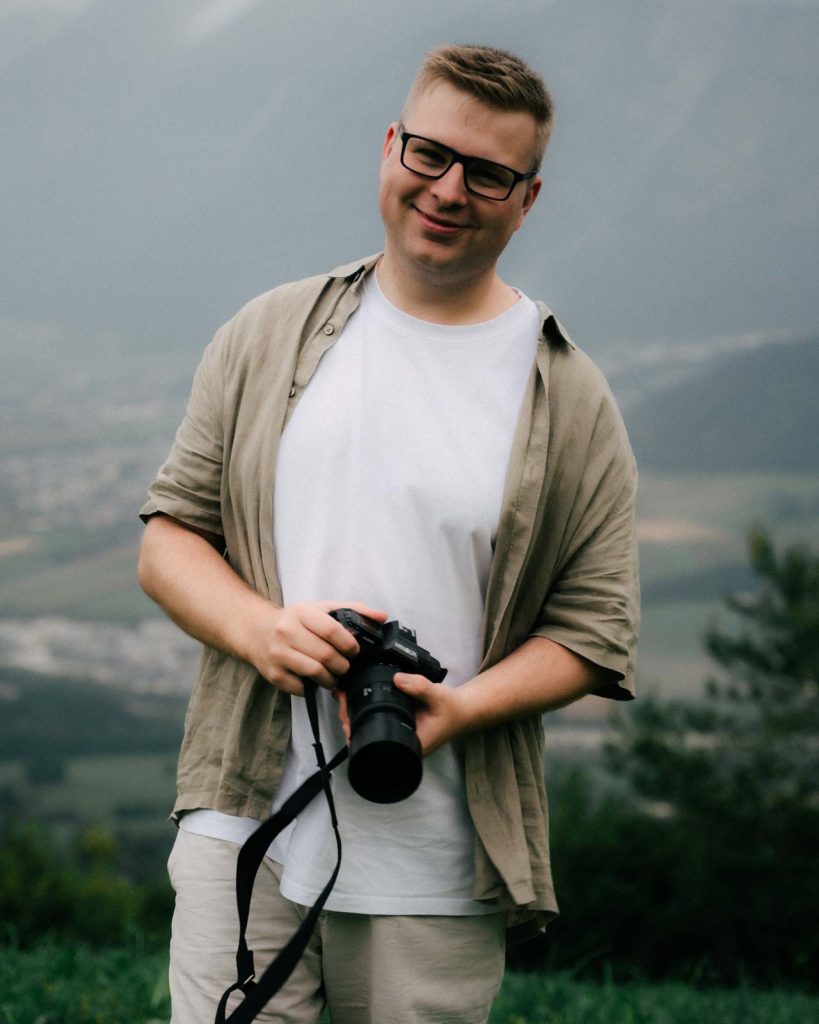 Julian Haberl, Gründer von JH‑Creative in Thaur, mit Kamera vor Alpenpanorama – professioneller Foto‑ und Videograf aus Tirol