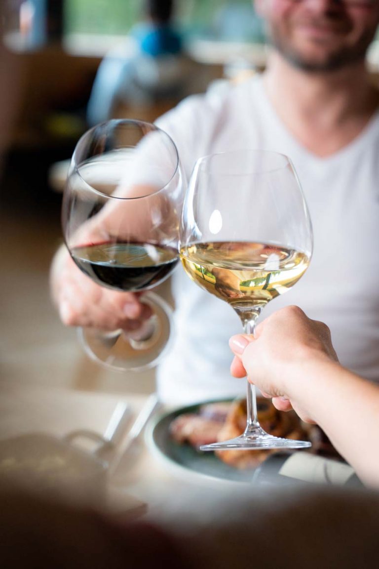 Gäste stoßen mit Rotwein und Weißwein im Restaurant der Umbrüggler Alm in Innsbruck an – stilvolles Genusserlebnis in Tirol.