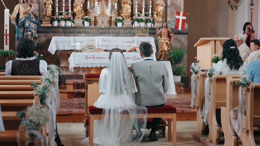 Kirchliche Trauung in Tirol: Braut und Bräutigam vor dem Altar, feierliche Atmosphäre im Hochzeitsfilm