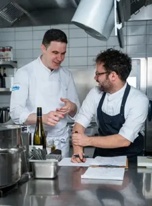 Zwei Köche besprechen Rezept und Menüplanung in professioneller Restaurantküche