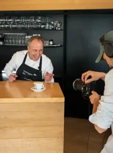 Barista hinter Theke wird bei der Zubereitung von Kaffee für Social Media Content gefilmt