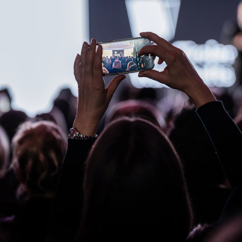 Besucher filmt Vortrag mit Smartphone bei einer Veranstaltung – Eventfotografie und Eventvideografie in Tirol.