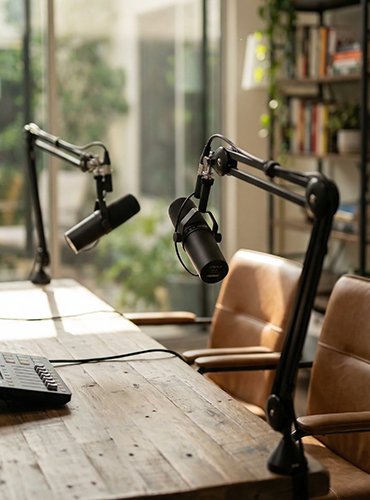 Podcast-Setup mit zwei Mikrofonen an einem Holztisch in heller, professioneller Gesprächsatmosphäre