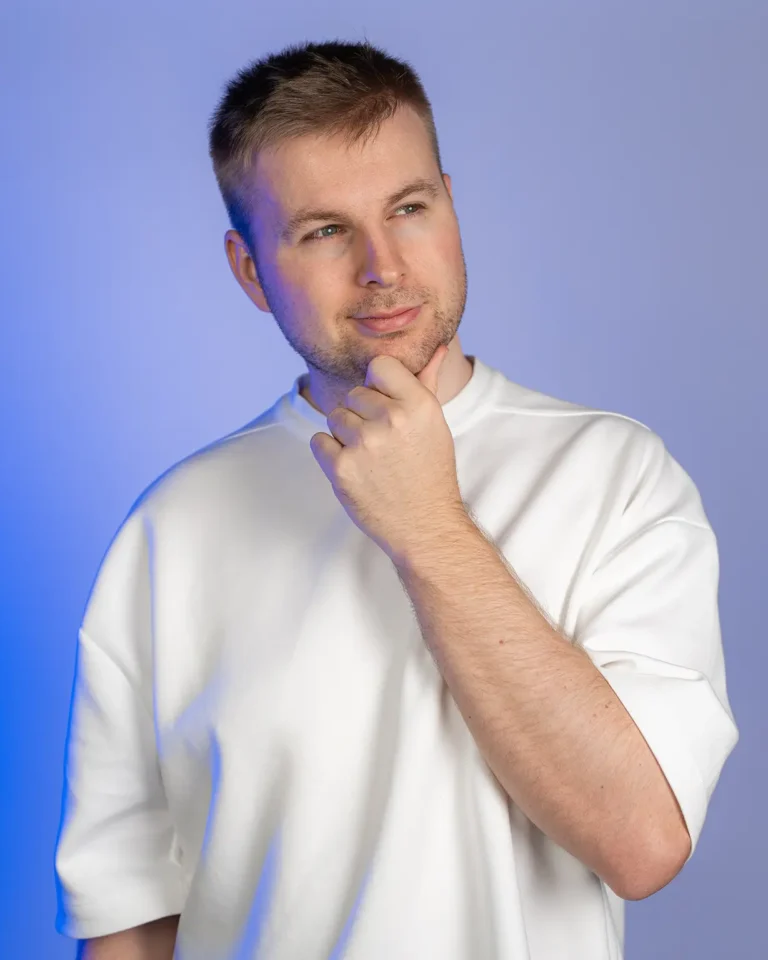 Julian Haberl von JH-Creative im Studio mit Hand am Kinn vor blauem Hintergrund